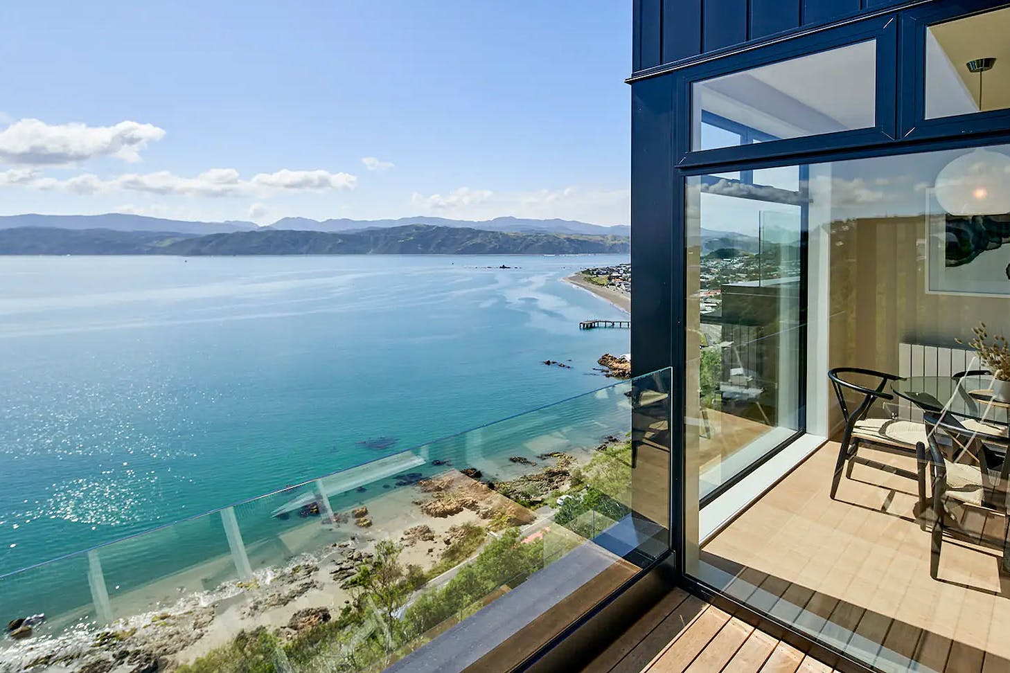 A peek from the balcony into the living area of the Harbour View Home shows off a marble countertop, stylish seating, and incredible sea views. Definitely one of the best Airbnbs in Wellington.